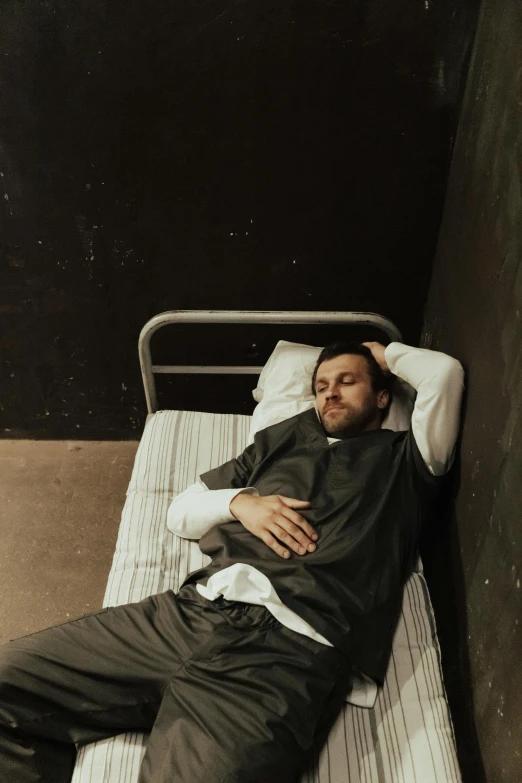 a man laying on top of a bed next to a wall, inspired by Elsa Bleda, pexels contest winner, renaissance, sad steven seagal in jail cell, at the hospital in patient gown, charlie day, worksafe. instagram photo