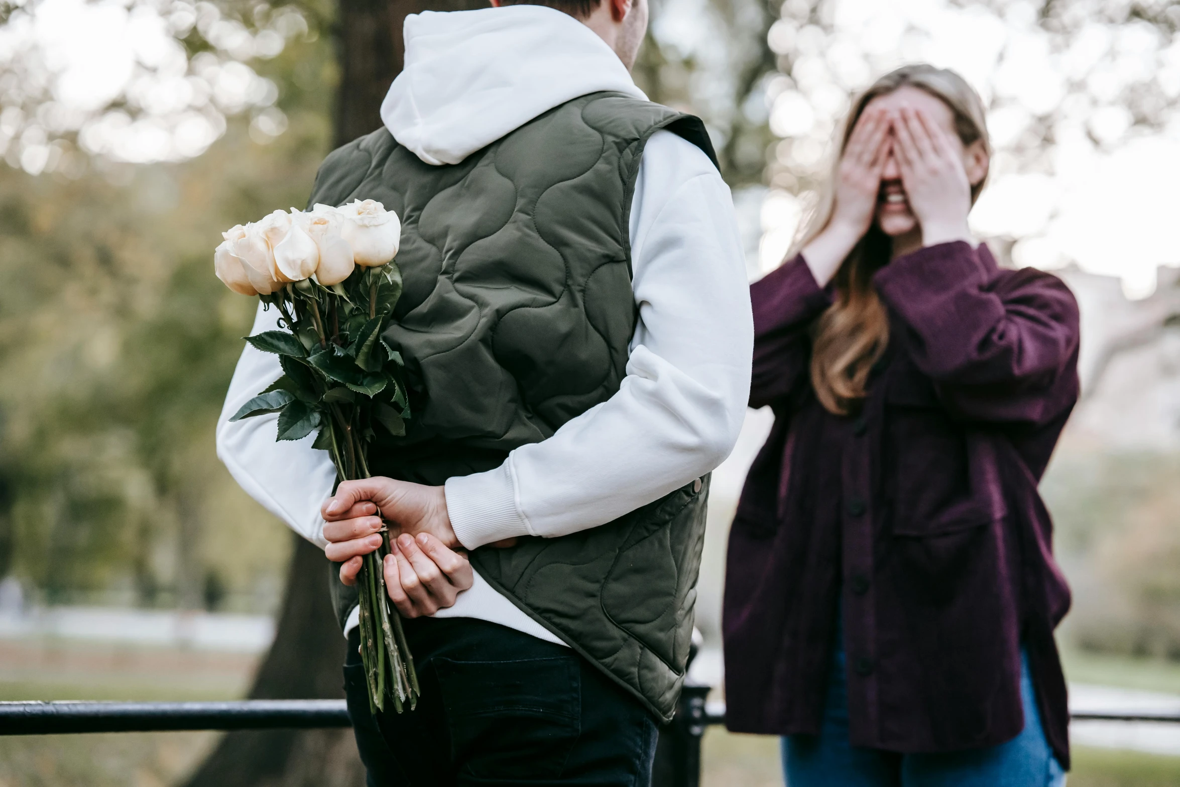 a man standing next to a woman holding a bunch of flowers, pexels contest winner, girl wearing hoodie, man proposing his girlfriend, ad image, hands behind back