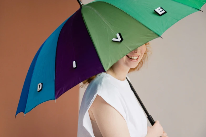 a woman holding a colorful umbrella over her head, inspired by Viktor de Jeney, unsplash, flat colour-block style, verbena, detail shot, upcycled