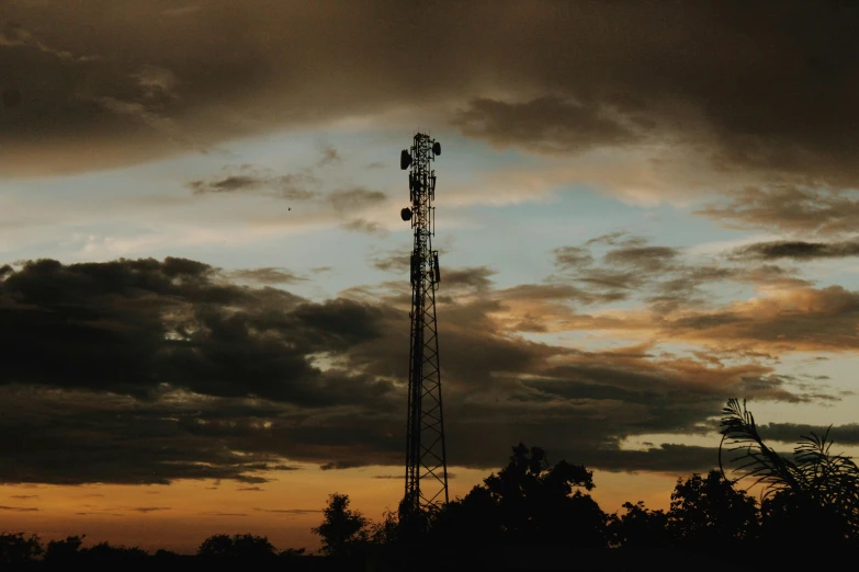 a cell phone tower is silhouetted against a cloudy sky, a portrait, by Carey Morris, unsplash contest winner, renaissance, late summer evening, floodlight, 2000s photo, shot on sony a 7 iii