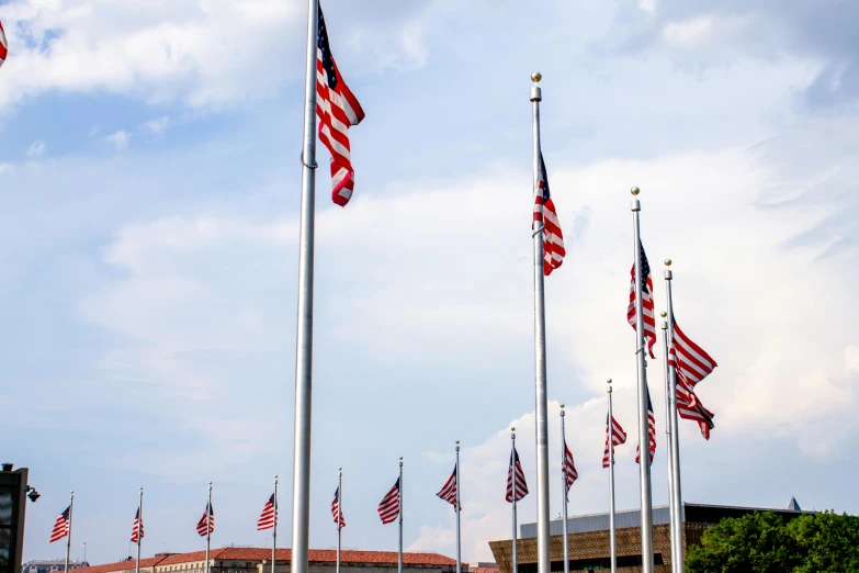 a row of american flags in front of a building, unsplash, visual art, capital plaza, set photo, thumbnail, 9/11