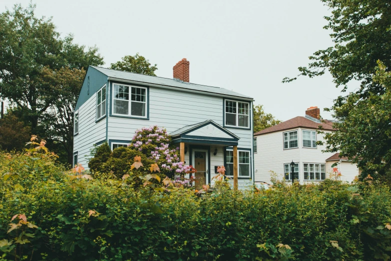 a white house sitting on top of a lush green field, a colorized photo, unsplash, arts and crafts movement, summer street near a beach, with soft bushes, seattle, cozy place