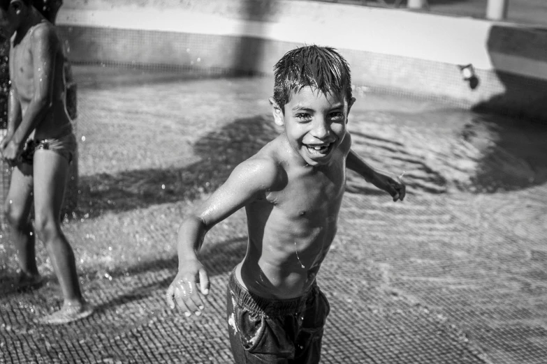 a black and white photo of a young boy playing in a sprinkler, disco smile, caio santos, playing at swiming pool, 15081959 21121991 01012000 4k