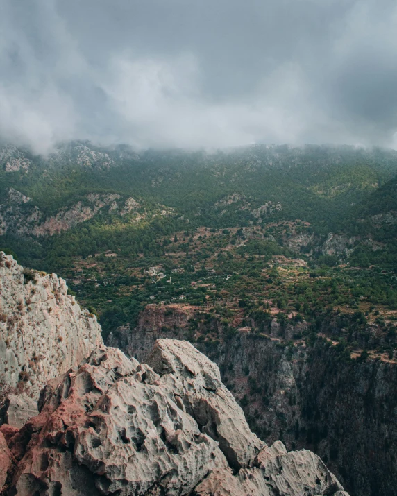 a group of people standing on top of a mountain, grey cloudy skies, cyprus, unsplash photography, huge chasm