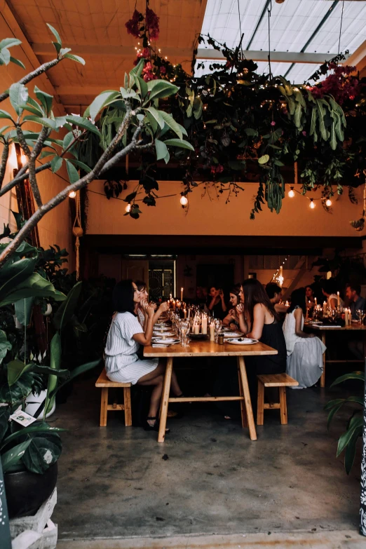 a group of people sitting at a table in a restaurant, unsplash, lush foliage, jakarta, panoramic shot, girls