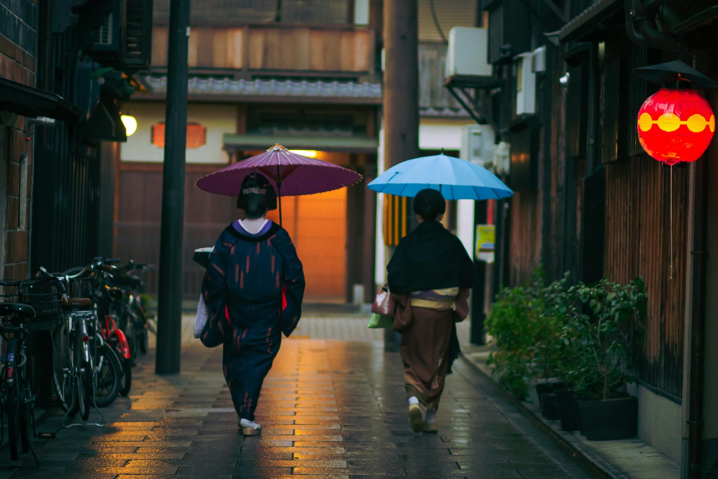 a couple of people walking down a street with umbrellas, inspired by Inshō Dōmoto, unsplash contest winner, in the evening, traditional clothing, 2 0 0 0's photo, fan favorite