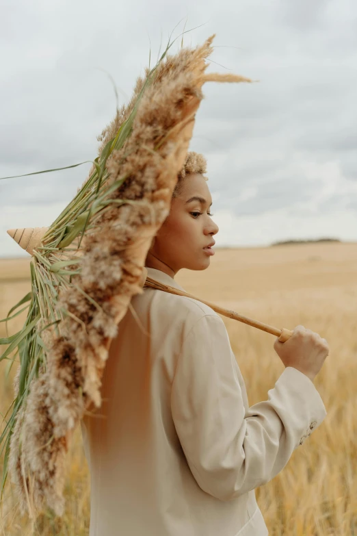 a woman standing in a field holding an umbrella, trending on pexels, renaissance, with textured hair and skin, wearing hay coat, bread, tan complexion
