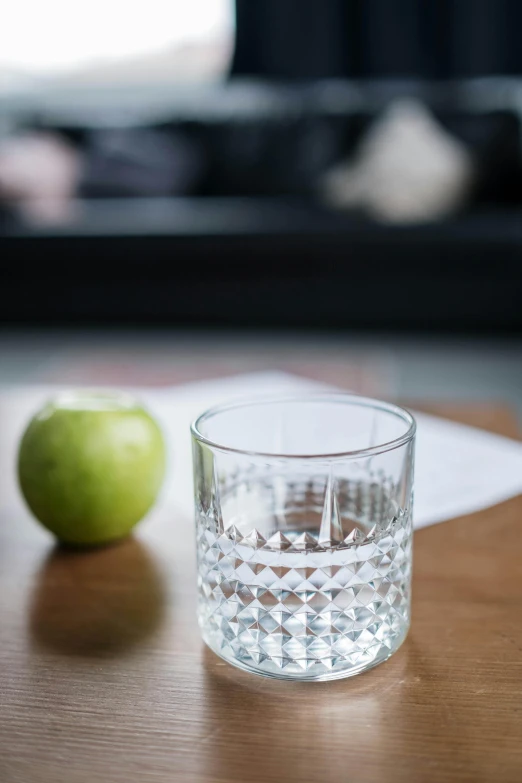 a glass of water and an apple on a table, by Nina Hamnett, unsplash, highly detailed refraction, slight grain, patterned, snacks