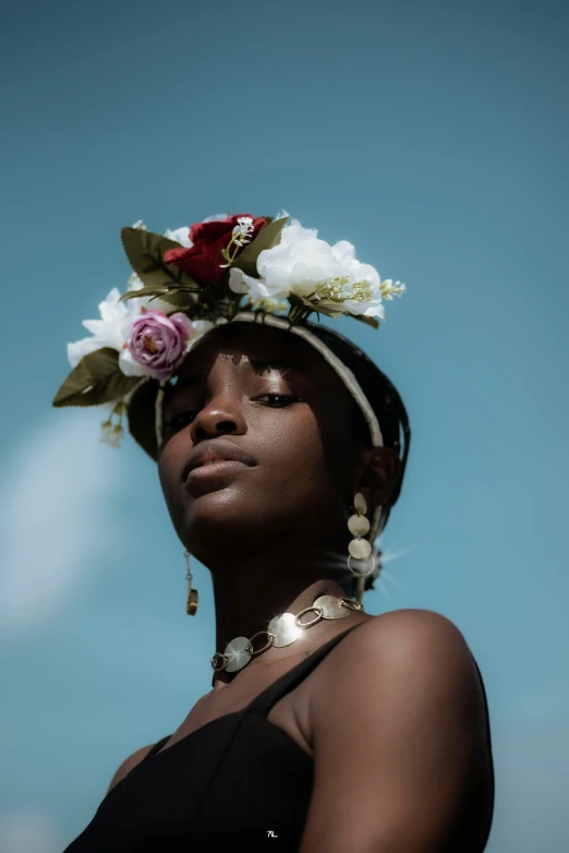 a woman with a flower crown on her head, trending on unsplash, afrofuturism, blue sky, dark complexion, mother of pearl jewelry, model pose