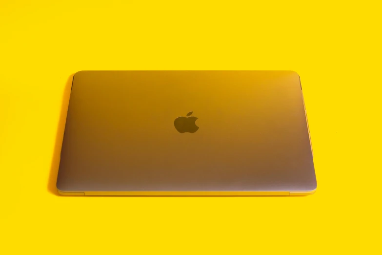 a laptop computer sitting on top of a yellow surface, by Carey Morris, pexels, computer art, apple orange, ignant, lacquered, back lit