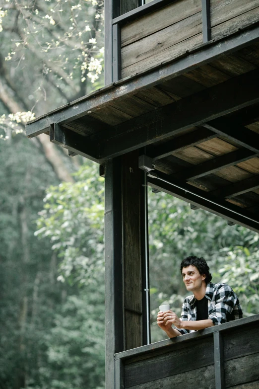 a man sitting on a porch reading a book, by Peter Churcher, unsplash, roofed forest, wearing a flannel shirt, breakfast at las pozas, in australia