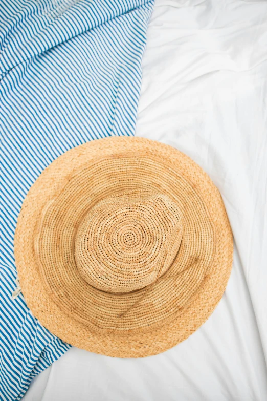 a straw hat sitting on top of a bed, by Nina Hamnett, trending on unsplash, striped shirt, dressed thobe, detailed product image, half image