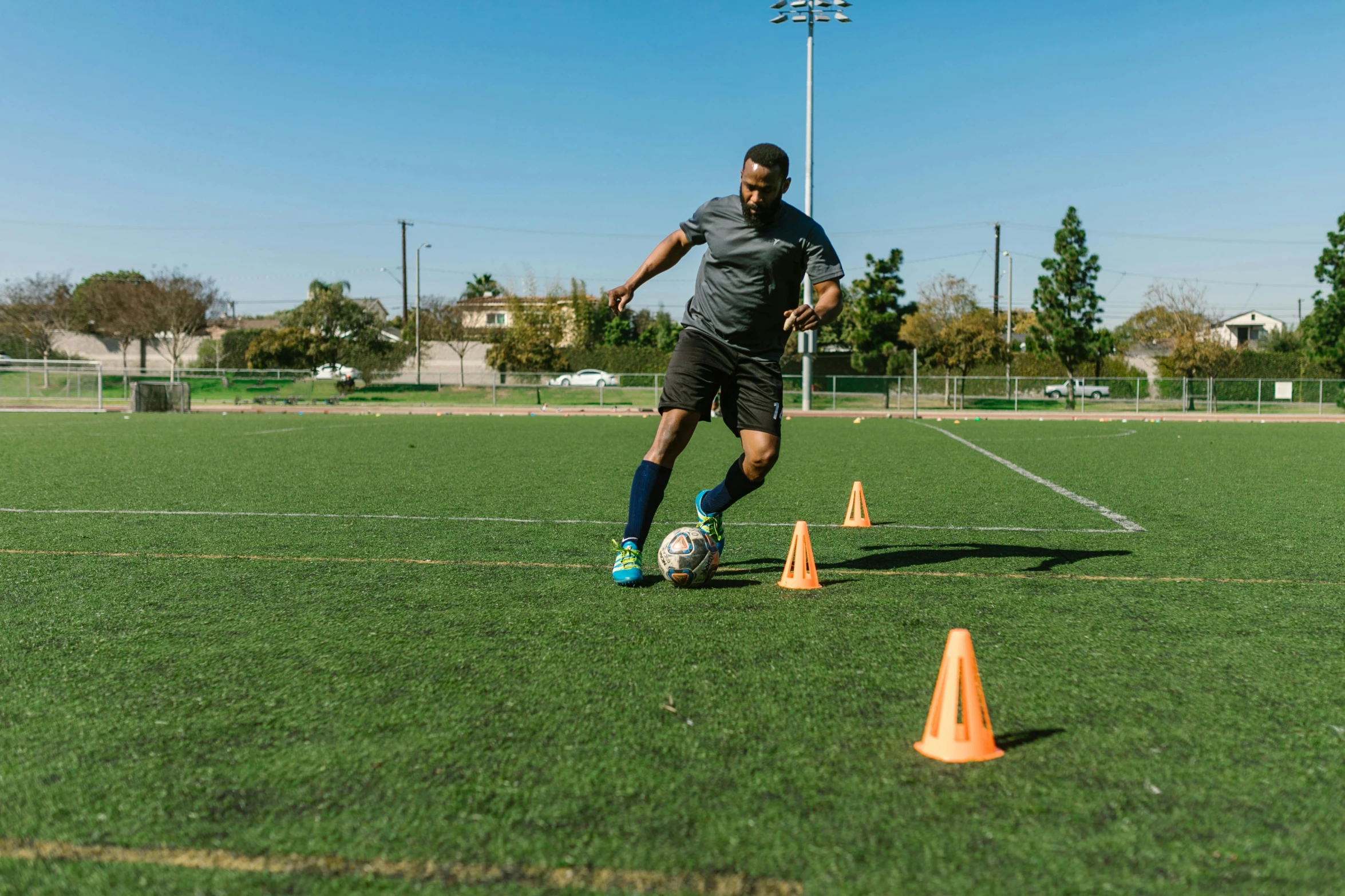 a man kicking a soccer ball on a field, bay area, hypersphere, george pemba, accurate walk cycle