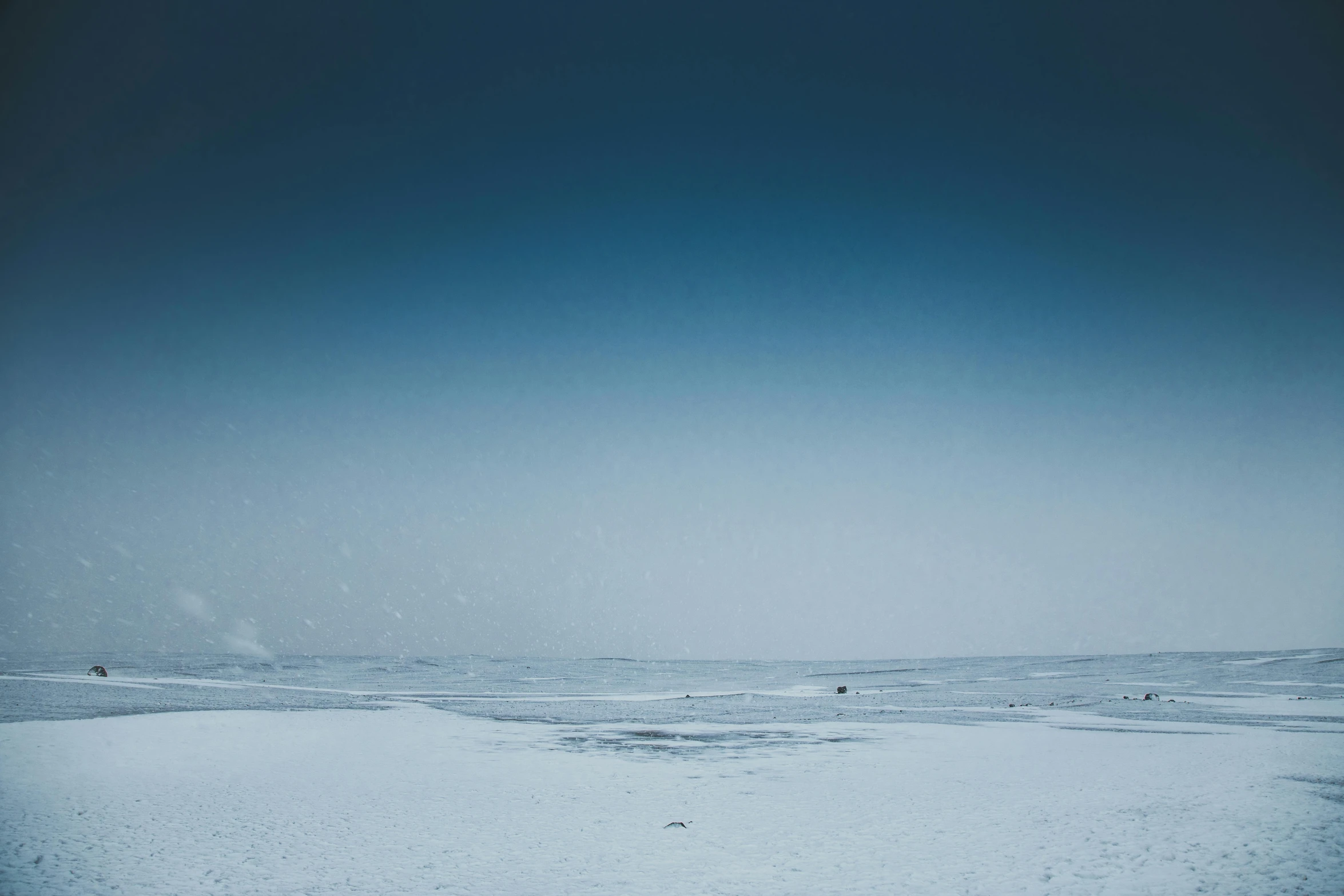 a man flying a kite on top of a snow covered beach, a picture, unsplash contest winner, minimalism, subtle blue, shot on hasselblad, snowing frozen ice, thumbnail