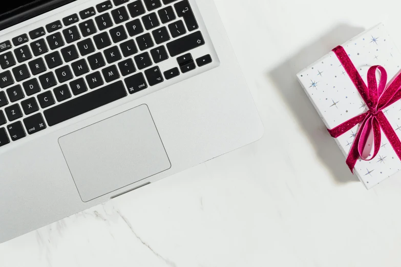 a laptop computer sitting on top of a table next to a present, trending on pexels, magenta and gray, white marble, mechanical keyboard, clean white background