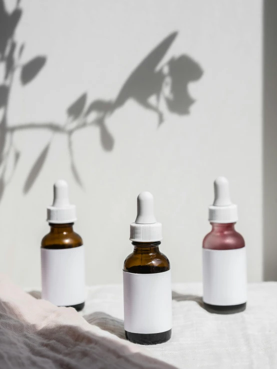 a couple of bottles sitting on top of a bed, on a white table, nootropic stimulant, partially cupping her hands, 3 - piece