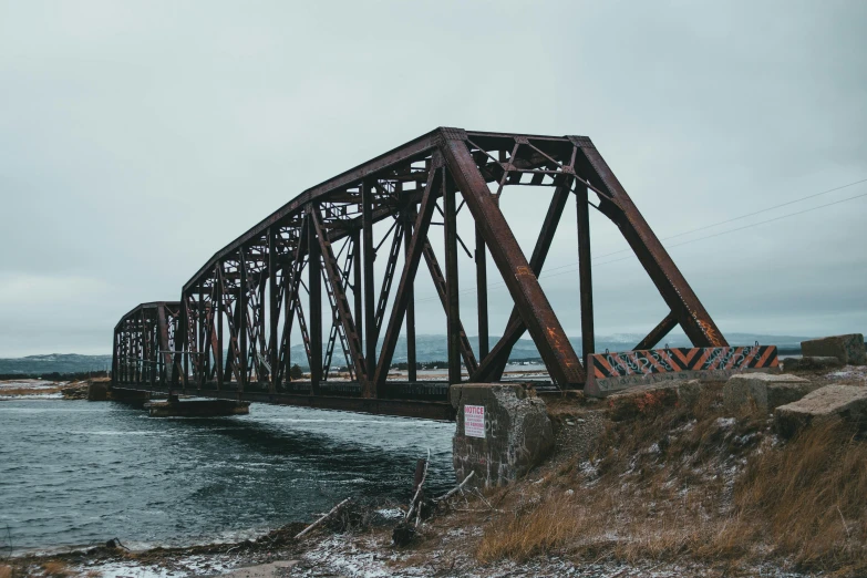 a train bridge over a body of water, pexels contest winner, heavy winter aesthetics, montana, ((rust)), ground level shot