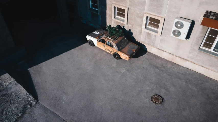 a van parked in front of a building with a christmas tree on top of it, inspired by Filip Hodas, unsplash contest winner, photorealism, in a wooden box. top down photo, brutalist courtyard, long shadow, old car