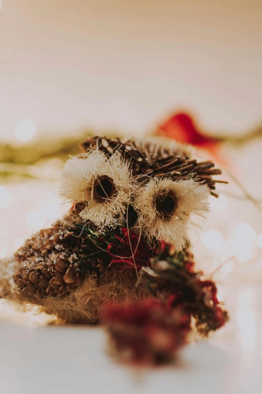 a close up of a stuffed animal on a table, by Andries Stock, pexels contest winner, process art, owl crown, festive, with soft bushes, natural materials