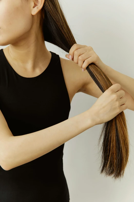 a woman brushing her long hair with a brush, an album cover, trending on pexels, depressed dramatic bicep pose, japanese, she is wearing a black tank top, hands in her hair. side-view