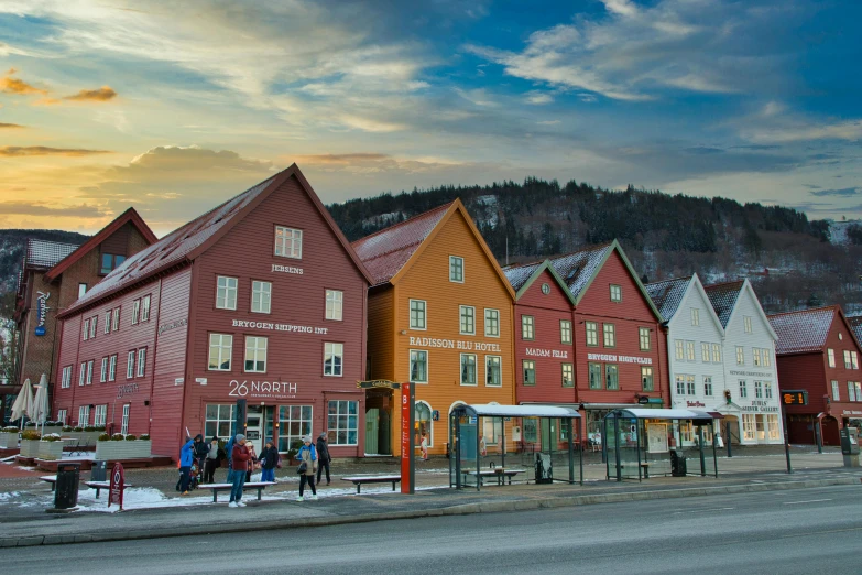 a group of buildings sitting on the side of a road, fjords, town square, peak experience ”, warm light