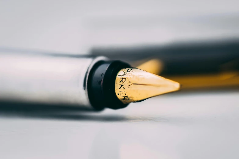 a fountain pen sitting on top of a table, a macro photograph, by Jesper Knudsen, unsplash, gold and silver ink, thumbnail, painted, ultra - realistic