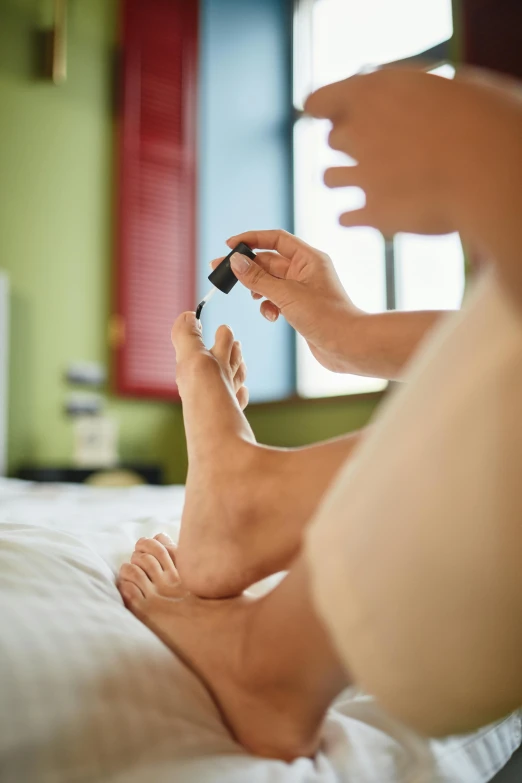 a person sitting on a bed using a cell phone, bare foot, spray, carefully crafted, high arches