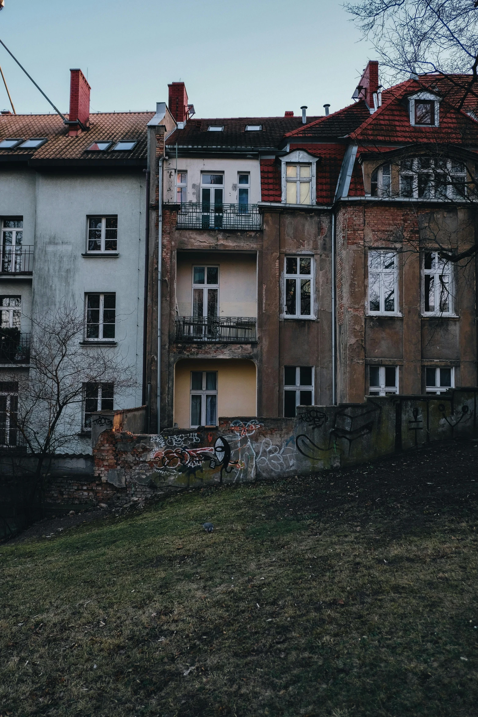 a couple of buildings sitting on top of a hill, by Adam Marczyński, pexels contest winner, graffiti, tenement buildings, muted colors. ue 5, standing outside a house, staggered terraces