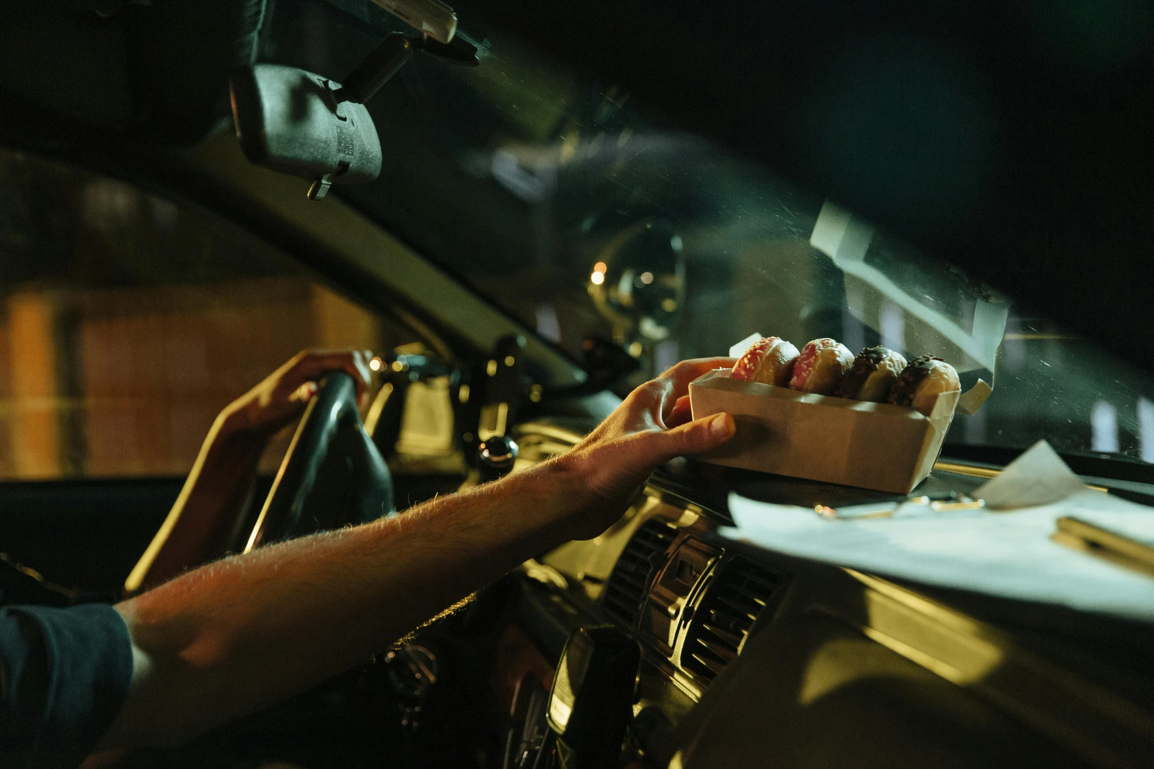 a man driving a car with a box of donuts in his hand, inspired by Elsa Bleda, alessio albi, nightlife, shot on sony a 7, rectangle