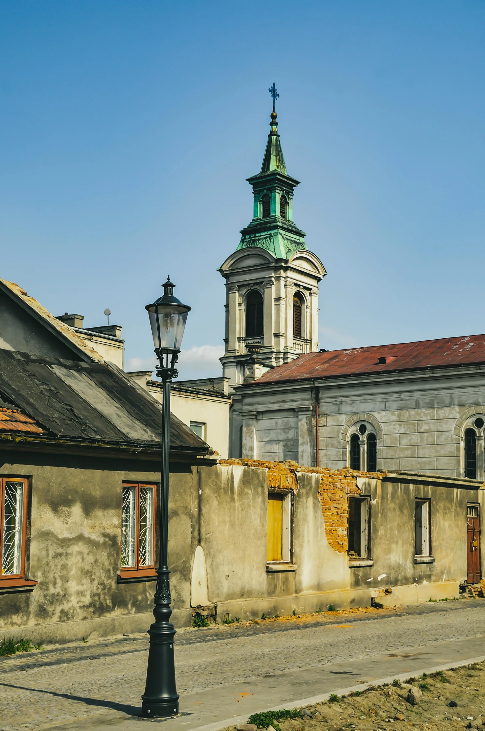 an old building with a clock tower in the background, inspired by Kazimierz Wojniakowski, baroque, green alleys, domes, sunny sky, taken in the early 2020s