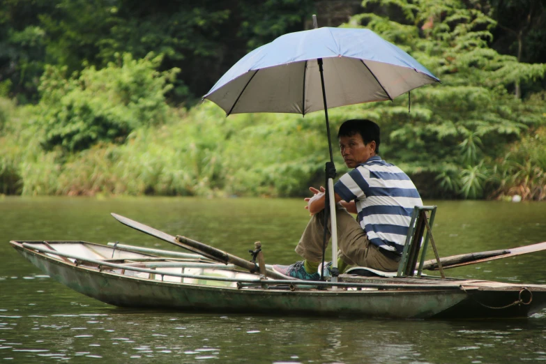 a man sitting in a small boat holding an umbrella, bao pham, avatar image