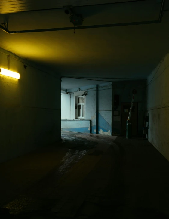 a dimly lit hallway leading to a building, inspired by Elsa Bleda, unsplash, abandoned car garage, low quality photo, post - soviet courtyard, very accurate photo