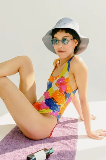 a woman sitting on top of a purple towel, in retro swimsuit, floral patterned skin, colorful lenses, lulu chen