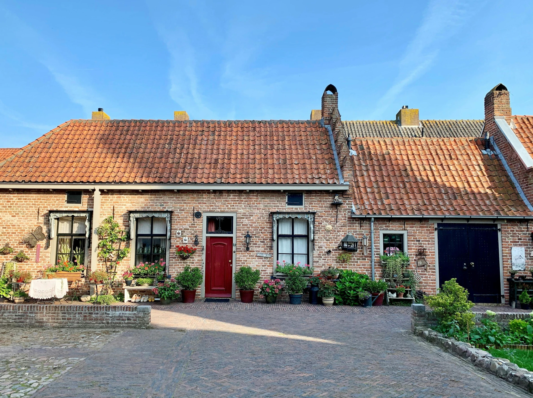 a large brick house with a red door, by Jan Tengnagel, pexels contest winner, verdadism, tiled roofs, het meisje met de parel, flowery cottage, contest winner 2021