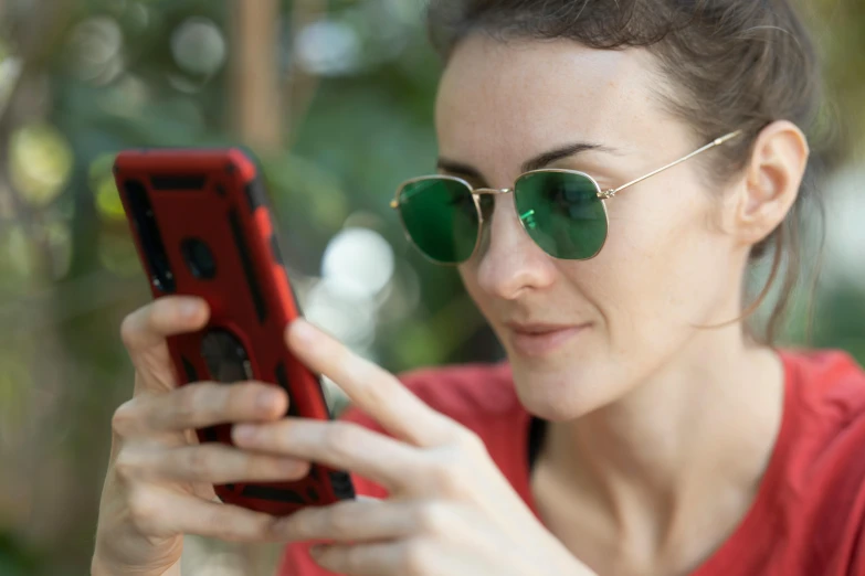 a woman wearing sunglasses looking at her cell phone, shades green and red, zoomed out, profile image, square rimmed glasses