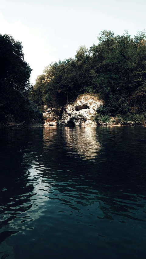 a body of water with trees in the background, by Mirko Rački, unsplash, sōsaku hanga, 1990s photograph, grotto, river confluence, low quality photo