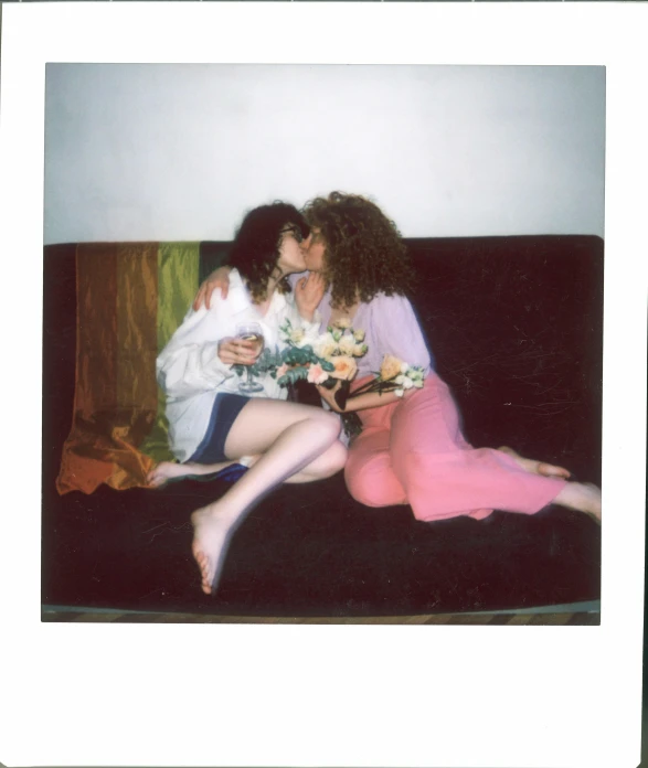 a couple of women sitting on top of a couch, a polaroid photo, inspired by Nan Goldin, trending on pexels, kitsch movement, sitting with flowers, finn wolfhard, hugging each other, expired color film