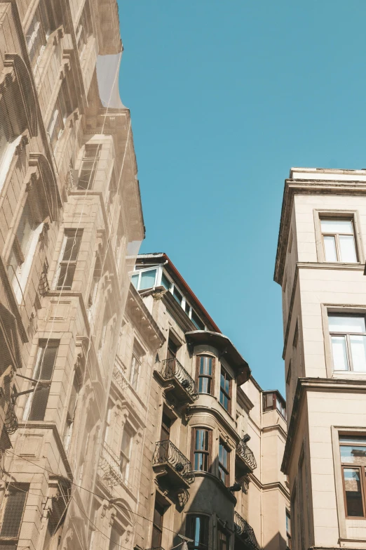 a couple of tall buildings next to each other, a picture, pexels contest winner, neoclassicism, beige, istanbul, street of teal stone, clear sky above