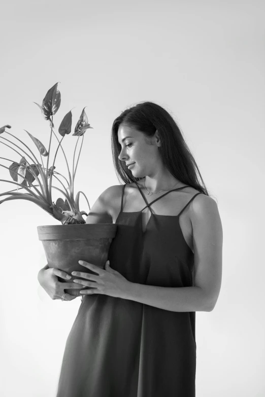 a black and white photo of a woman holding a potted plant, pexels contest winner, she is wearing a black tank top, alanis guillen, sustainable materials, profile pic