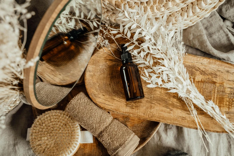 a bottle of essential oil sitting on top of a wooden cutting board, a still life, by Emma Andijewska, trending on pexels, arts and crafts movement, brown and cream color scheme, dried fern, thumbnail, skincare