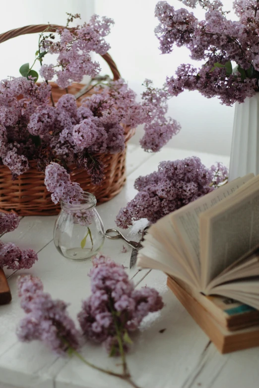 a basket of flowers sitting on top of a table, pexels contest winner, romanticism, light purple, open books, lilacs, indoor shot