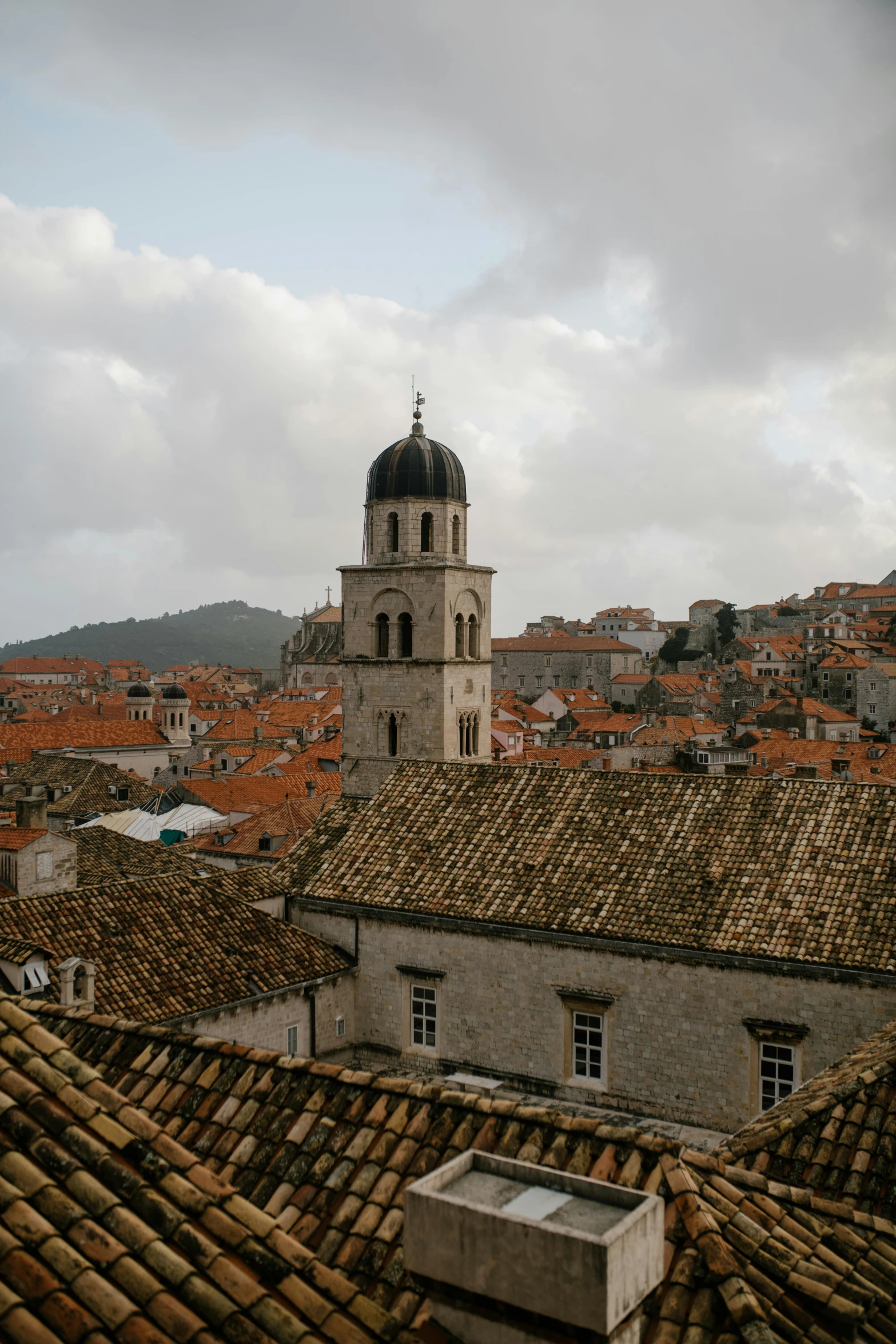 a view of a city from the top of a building, by Emma Andijewska, pexels contest winner, baroque, dubrovnik, low quality photo, grey sky, roof background