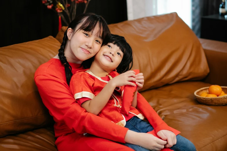 a woman and a child sitting on a couch, pexels contest winner, hurufiyya, wearing red clothes, young asian girl, avatar image, girl wearing uniform