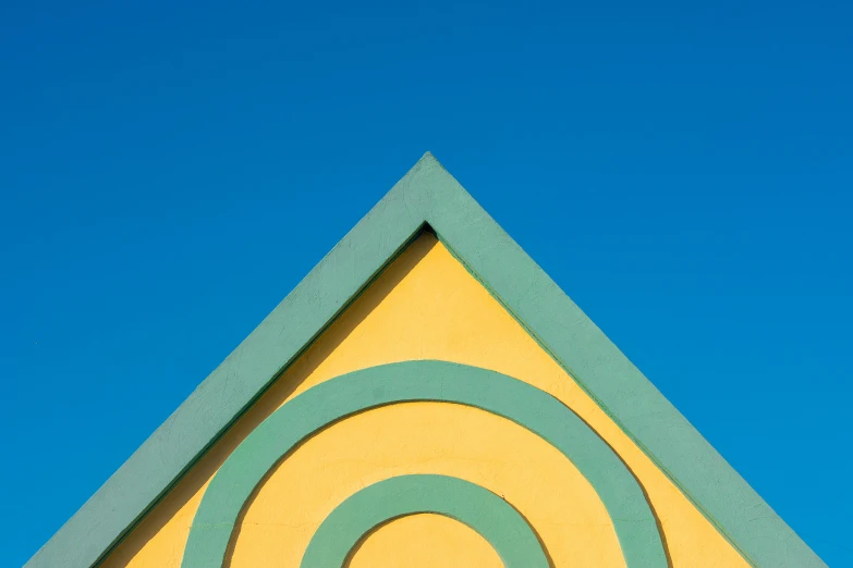 a yellow building with a blue sky in the background, an abstract sculpture, inspired by Wes Anderson, unsplash contest winner, concentric circles, colors of jamaica, in triangular formation, minimalist photorealist