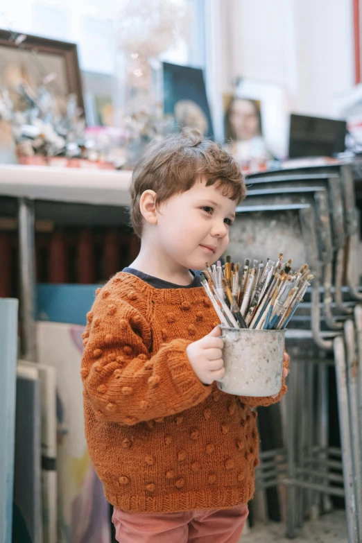 a little boy holding a pot full of paint brushes, pexels contest winner, process art, very handsome, many treasures, small freckles, weta workshop