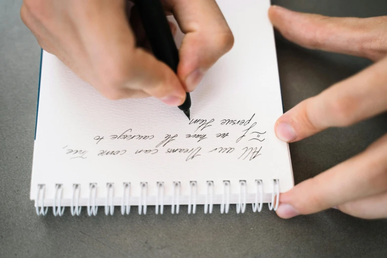 a person writing on a notebook with a pen, letterism, thumbnail, high quality image, trending photo, fan favorite