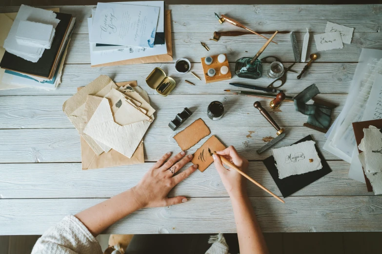 a person sitting at a table working on a piece of paper, trending on pexels, arts and crafts movement, leather apron, avatar image, pyrography, postage