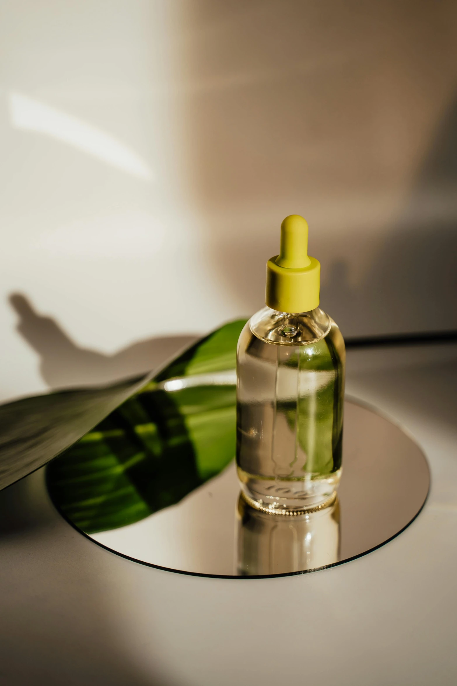 a bottle of liquid sitting on top of a table, by Julia Pishtar, skin care, manicured solarpunk greenery, glossy yellow, colour photograph