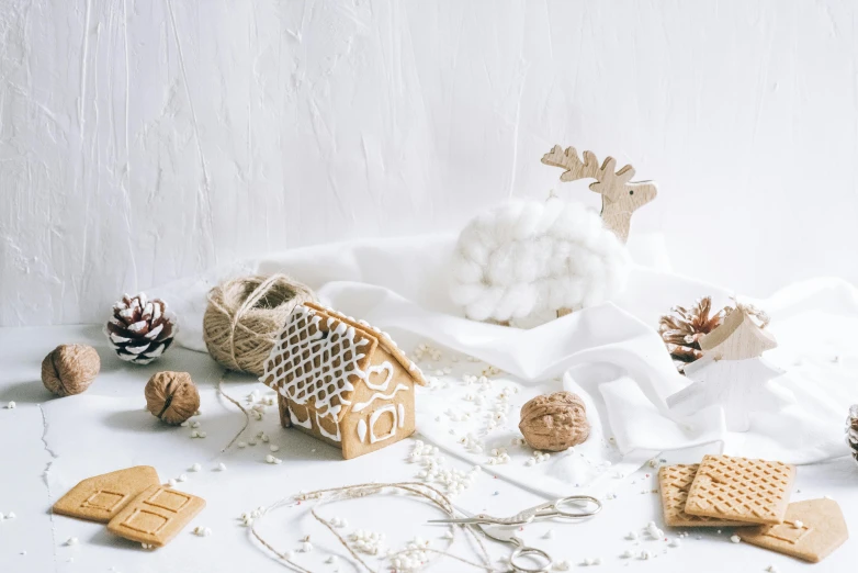 a white table topped with cookies and christmas decorations, a cross stitch, trending on pexels, visual art, background image, white minimalist architecture, made of beads and yarn, whipped cream