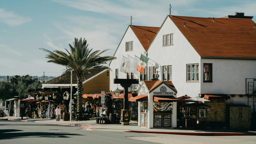 a couple of buildings sitting on the side of a road, pexels contest winner, arts and crafts movement, oceanside, lots of shops, restaurant, americana architecture